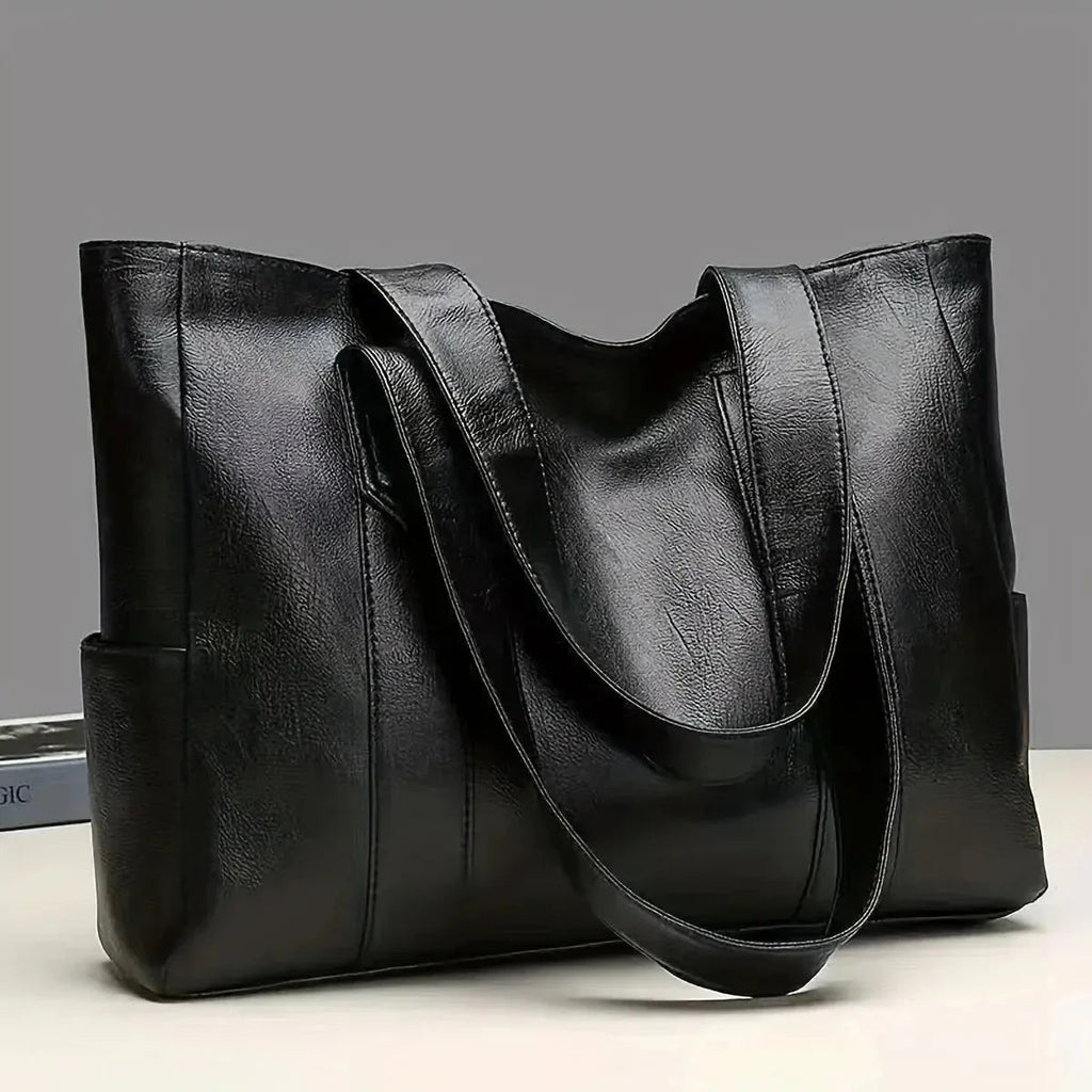Black leather tote bag on a light gray background
